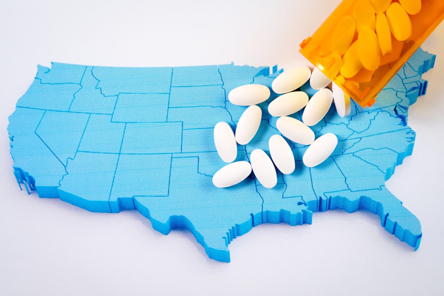 Canva-White-pharmaceutical-pills-spilling-from-prescription-bottle-over-American-flag-min-1536x1024.jpg